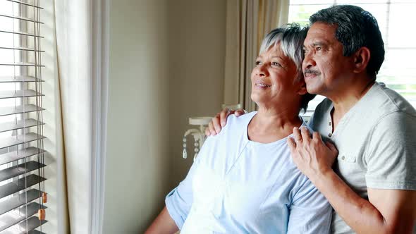 Senior couple looking through window 4k