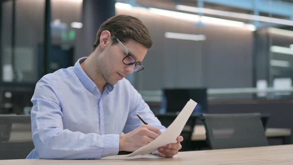 Young Man Reading Documents at Work