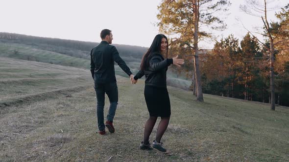 Newly Engaged Charismatic and Happy Young People Walk in Nature Holding Hands the Woman Turns to