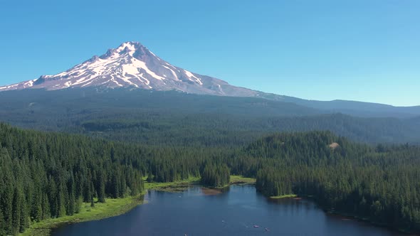 Aerial drone flying above Trillium Lake toward snow covered Mt. Hood in summer time.