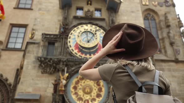 woman in hat and backpack near famous clock in Prague, Czech Republic