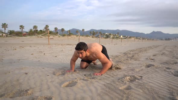 muscular athlete doing frog jumps shirtless on the beach metabolic training