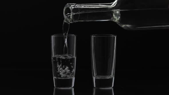 Pouring Up Two Shot of Vodka From a Bottle Into Glass, Black Background