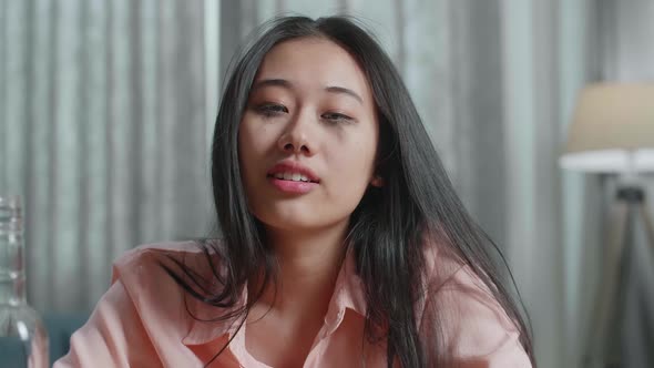 Close Up Of Drunk Asian Woman Drinking Vodka And Looking At Camera At Home