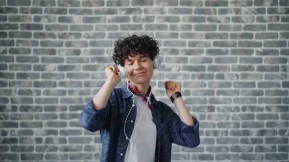 Portrait of Joyful Woman Listening To Music in Headphones and Dancing Alone