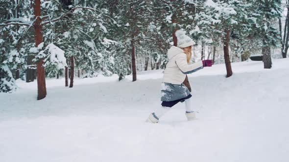 Little girl is running in the snow and falling into it in winter.