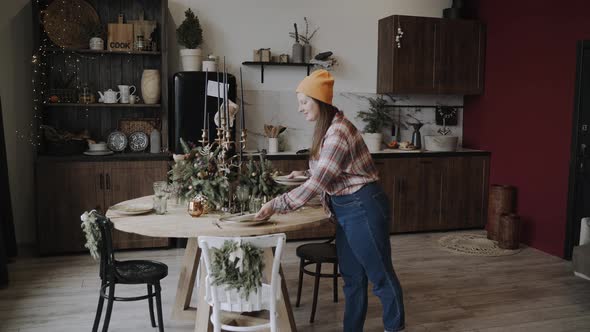 Plump Woman Serves and Arranges the Plates on the Festive Christmas Table