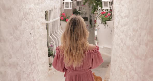 Following Shot Of Attractive Woman Relaxing Near White Buildings On Popular Greece Resort