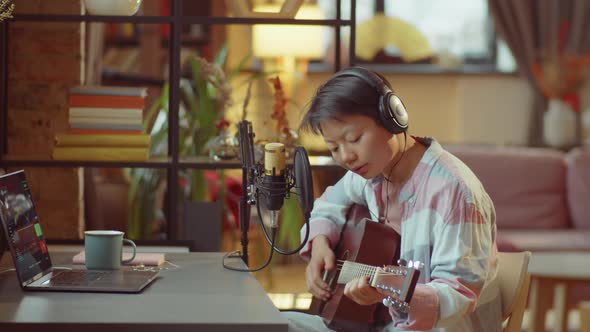 Asian Woman Playing Guitar and Recording Song in Home Studio