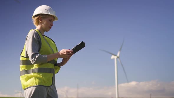 Professional Standing Near Wind Mill and Making Inspections