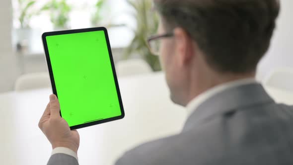 Man Looking at Tablet with Green Chroma Screen