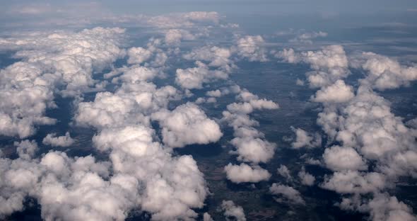 aerial footage shot from high altitude plane with clouds spotted throughout as weather meteorologica