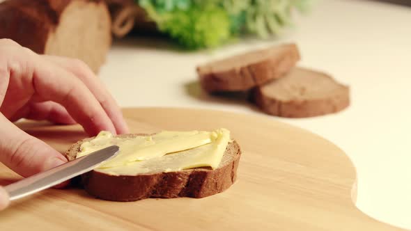 Early in the Morning a Woman Prepares a Sandwich for Her Family Spreads Organic Butter on the Bread