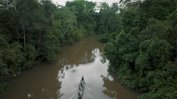 Ascending Aerial view showing people sitting in kayak boat and cruising in amazon rainforest