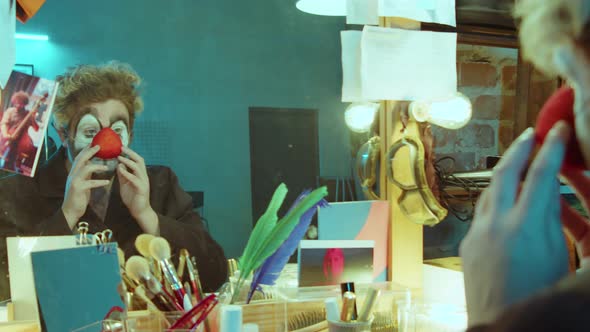 Clown Making Faces in front of Mirror in Dressing Room