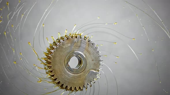 Super Slow Motion Shot of Rotating and Splashing Metal Cogwheel on Grey Background at 1000 Fps