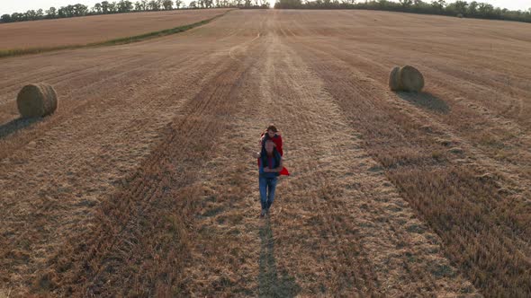 Farther Running Across Field with Son on Shoulders