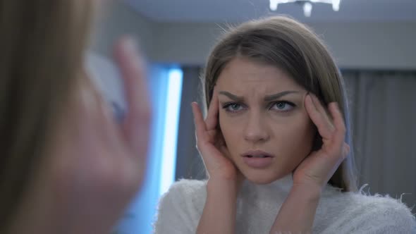 Tired Woman with Headache Looking in Mirror