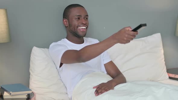 Young African Man Watching Television in Bed