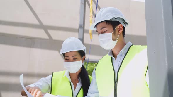 Asian colleague workers people wear protective safety helmet and face mask onsite of architecture.