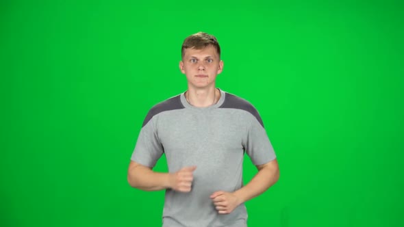 Young Man Runs and Tires on a Green Screen. Slow Motion