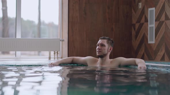 Visitor of Modern Balneological Center is Relaxing in Large Swimming Pool with Thermal Water