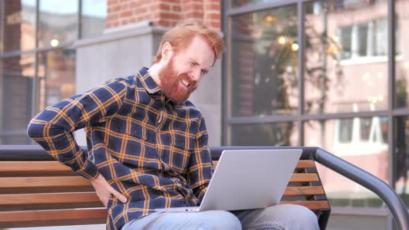 Redhead Beard Young Man with Back Pain Working on Laptop Outdoor