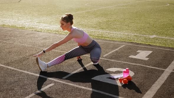 Young Fitness Girl Doing Stretching on the Stadium Summer in Sunny Weather.