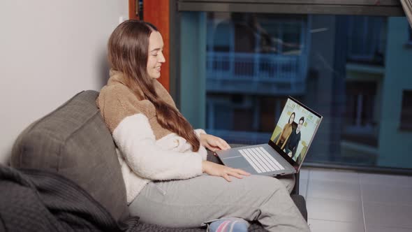 Young Happy Pregnant Woman Enjoying Video Call with Friends on Laptop While Relaxing on Sofa