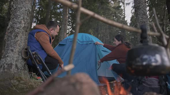 A Couple of Lovers are Setting Up a Tent Throwing a Canopy Over the Tent