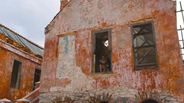 Girl in bikini standing in window opening of abandoned lighthouse