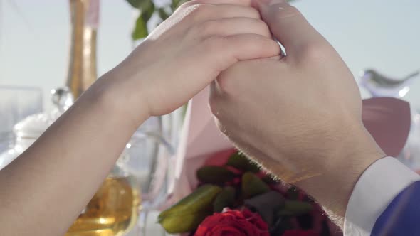 Young Couple Sitting Together Holding Hands on the Restaurant Table with