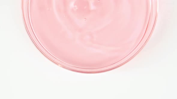 Transparent Pink Cosmetic Liquid Dripping in a Glass Bowl of Petri