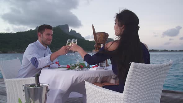 A man and woman couple dining on a deck pier at night in Bora Bora tropical island.