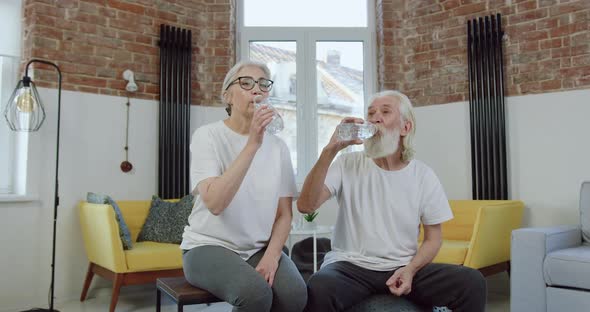 Old Couple in Sports Uniform Drinking Water After Joint Home Workout