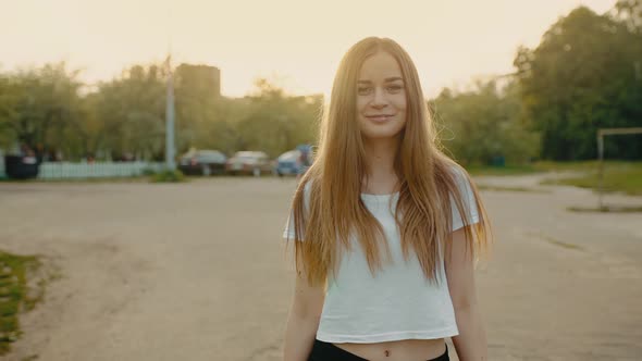 A Young Girl Walks Towards the Camera in the Park and Smiles