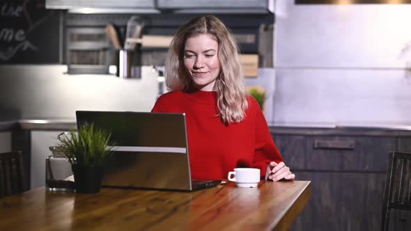 Portrait of happy girl enjoying unexpected good news on a laptop in kitchen