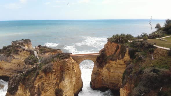 Stone Bridge connecting eroded cliffs in Student Beach In Lagos, Algarve, Portugal 