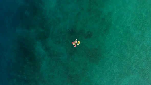 Aerial view of group holding hands on inflatable mattress on Atokos island.