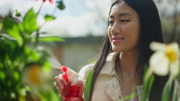 Portrait of Smiling Proud Young Female Gardener Florist Spraying Water on Red Blooming Flowers in