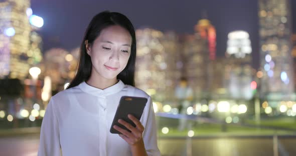 Woman using smart phone at night in the city