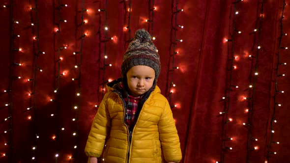 Young boy posing serious in front of lights wall at Christmas market.