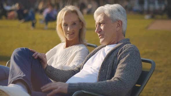 Senior Joyful Couple Sitting Together on Bench at Park