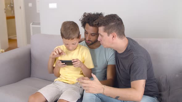 Focused Boy Sitting on Dads Lap and Playing Online Game