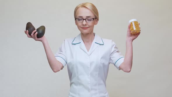 Nutritionist Doctor Holding Organic Avocado Fruit and Jar of Medicine or Vitamin or Omega 3 Capsules