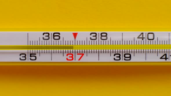Temperature Rising Shown on a Thermometer on a Yellow Background Closeup