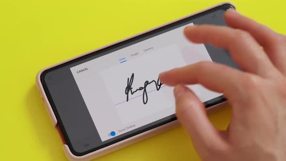 Electonic signature with finger in phone screen on yellow background desk.