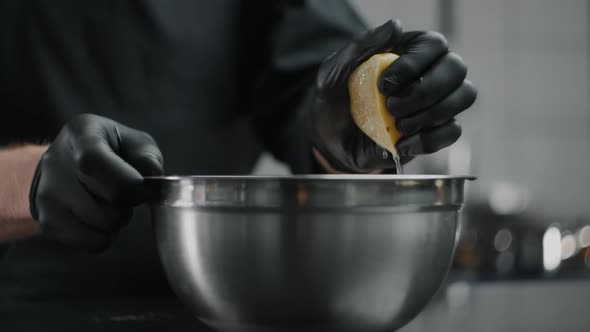 Chef in Black Gloves Squeezes Lemon To the Metal Bowl in Slow Motion, Lemon Sprinkles, Raw Natural