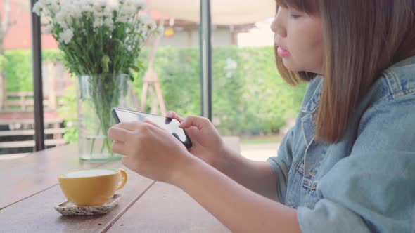 Female blogger photographing in cafe with her phone. A young woman taking photo of coffee.