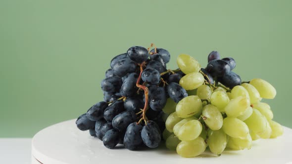 Close Up, Black and White Grapes on Rotating Table Isolated on Green Background